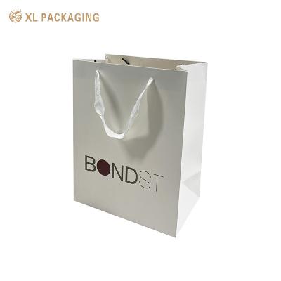 China Bolso de papel personalizado profesional de borde blanco blanco uno para comprar ropa zapatos empaque bolsa de compras con logotipo en venta