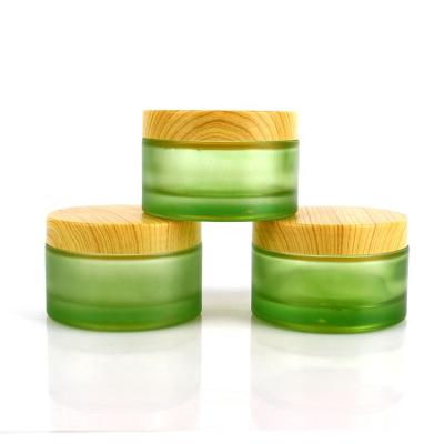 China Wholesale 200g Round Skin Care Cosmetic Container Frosted Green Glass Cosmetic Jars With Wood Grain Lid 200ml for sale