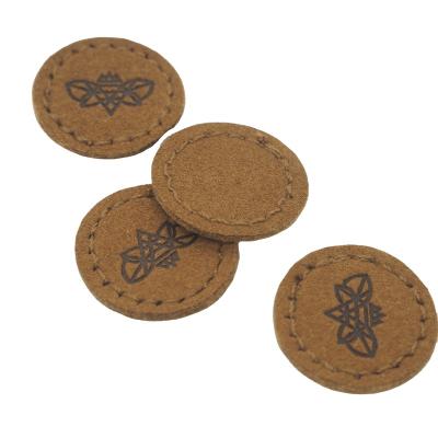 China Sustainable Customized Debossed Embroidered Suede Leather Round Leather Label For Clothing Bags for sale