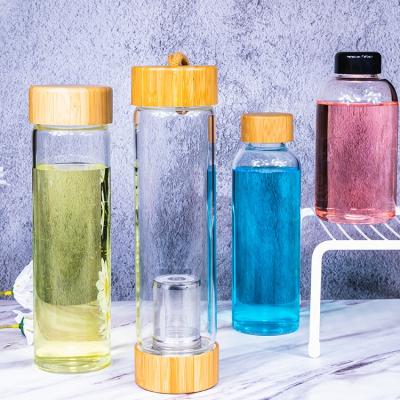 China Viable Bubble Tea Glass Water Bottle With Double Bamboo Lid Mesh Filter Glass Water Bottle for sale