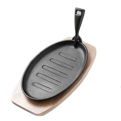 China Traditional Restaurant Steak Pan Preseasoned Cast Iron Skillet Frying Sizzling Dish with Wooden Bottom Sizzling Dish for sale