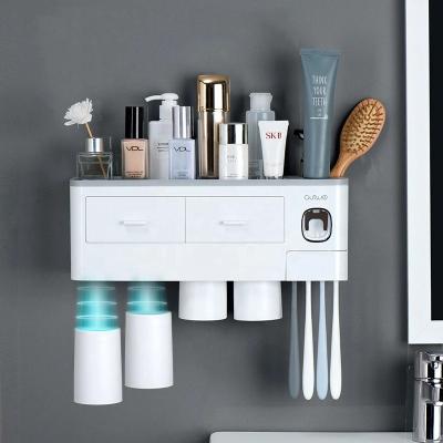 China Automatic Household Magnetic Adsorption Inverted Toothbrush Holder Toothpaste Dispenser With Cup Toothpaste Bathroom Accessories Set for sale