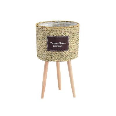 China Minimalist Home Decor Woven Planter With Wooden Stand Woven Plant Basket On Wooden Leg Wholesale for sale