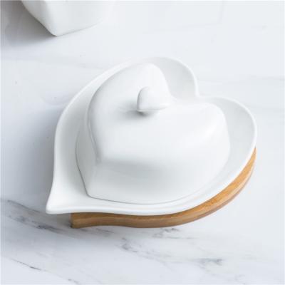 China Sustainable New Arrivals Heart Shape White Butter Container Ceramic Butter Dish With Wooden Lid And Tray for sale