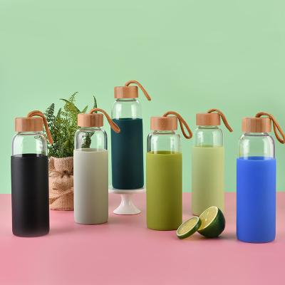 China Viable Custom Colored Bamboo Sleeve Heat Resistant Silicone Lid Sports Glass Water Bottle for sale