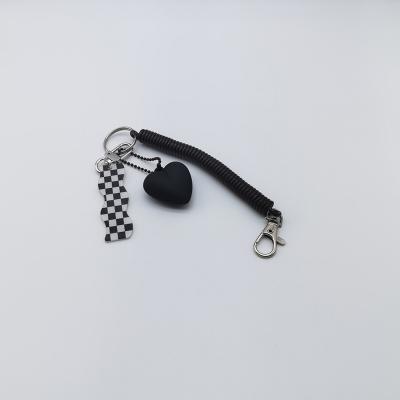 China Simple black heart shaped key chain has a retractable rubber spring and a black and white acrylic pendant for sale