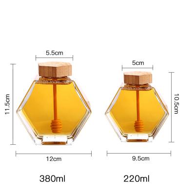 China Luxury Kitchen 220ml 380ml Hexagonal Bee Shaped Glass Honey Jar Container Freshness Preservation With Wooden Spoon Lid for sale