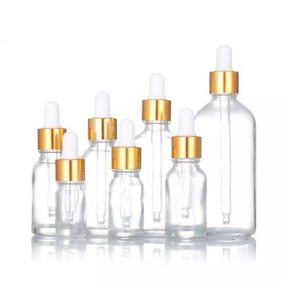 China Cosmetic Transparent glass serum hair oil bottle gold dropper body essential oil bottles 5ml 10ml 15ml 30ml 50ml 100ml for sale